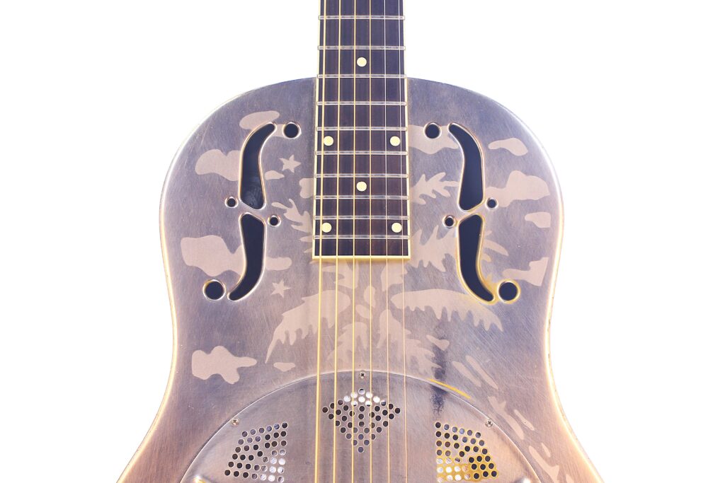 Nahaufnahme Des Korpus Der National Reso-Phonic Style O 2009 Akustik Gitarre Mit Verzierten Metallarbeiten Und Zwei F-Förmigen Schalllöchern, Die Die Dekorativen Gravuren Auf Weißem Hintergrund Hervorheben.