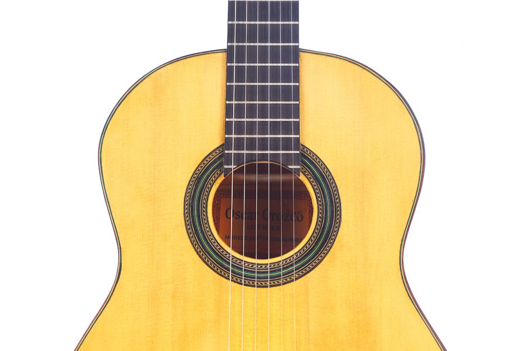 Nahaufnahme Von Korpus Und Hals Der Oscar Orozco 2023 Santos Hernández Flamenco-Gitarre Mit Heller Holzoberfläche, Sichtbarem Schallloch, Dekorativer Rosette Und Nylonsaiten Auf Weißem Hintergrund.