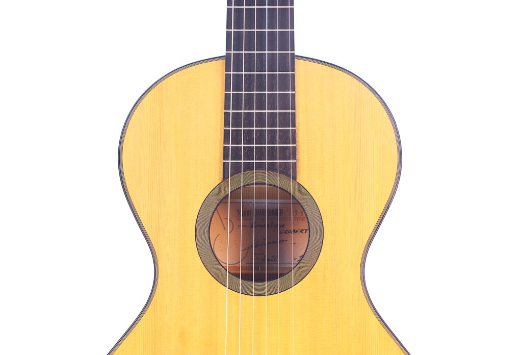 Nahaufnahme Des Korpus Und Des Halses Der Grobert Romantikgitarre 2016 Von Yoann Charbonnier. Hervorzuheben Sind Die Helle Holzoberfläche, Das Schallloch, Die Saiten Und Ein Teil Des Griffbretts Vor Einem Weißen Hintergrund.