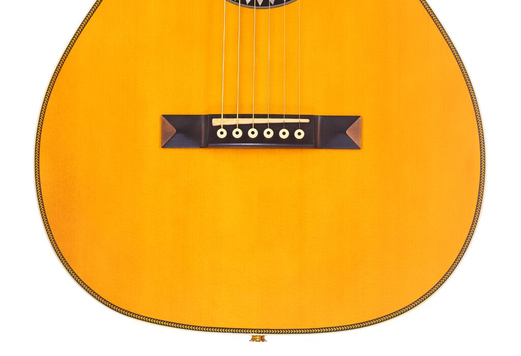 Nahaufnahme Der Martin 0-28 Ian Anderson Akustik Gitarre Mit Schwerpunkt Auf Den Saiten, Dem Steg Und Dem Hellen Holzkorpus Mit Dekorativen Randdetails.