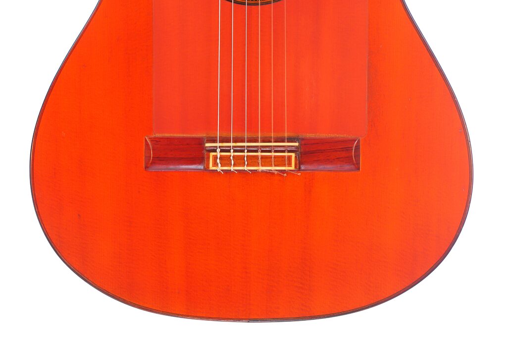 Nahaufnahme Der Unteren Hälfte Der Faustino Conde Flamenco-Gitarre Von Hermanos Conde 1983. Hervorzuheben Sind Die Saiten, Der Steg Und Ein Teil Des Hellen, Rotbraunen Holzkorpus.