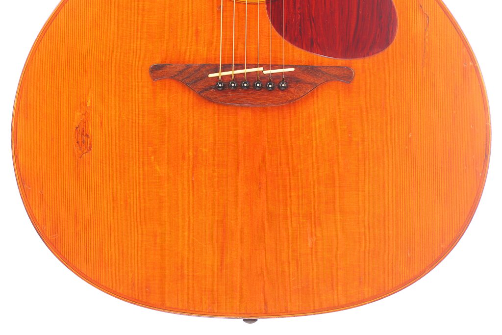 Nahaufnahme Des Korpus Der Lowden F-9 1980 Akustik-Gitarre, Die Das Warme Orangefarbene Holzfinish, Den Sichtbaren Steg, Die Saiten Und Einen Teil Des Dunkel Gefärbten Schlagbretts Zeigt.