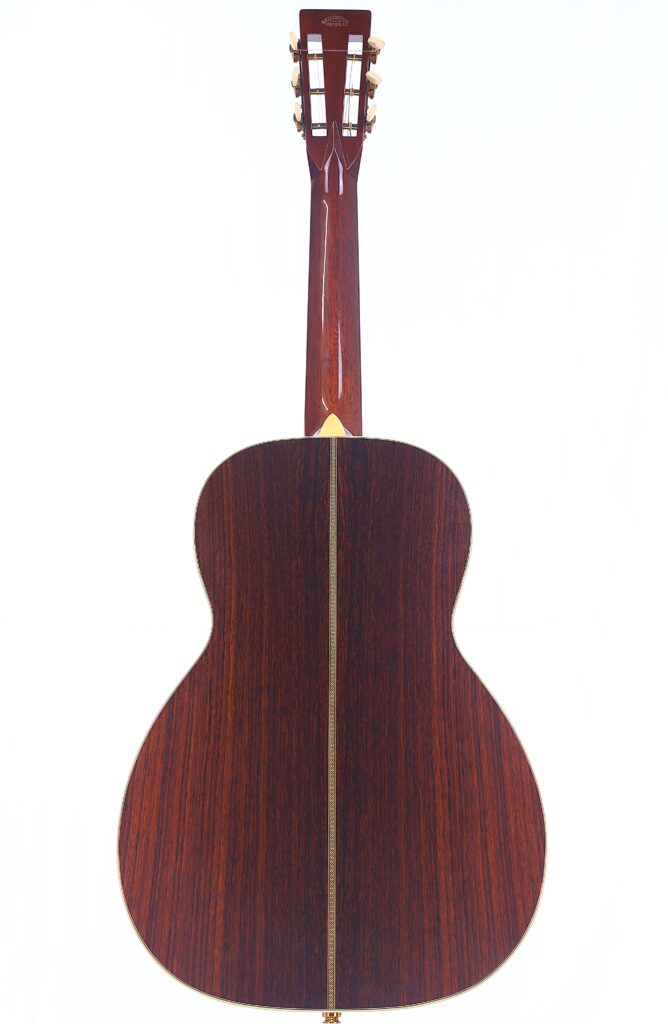 Die Martin 0-28 Ian Anderson Akustik Gitarre Hat Einen Polierten Dunklen Holzboden Mit Einer Hellen Vertikalen Einlage, Ergänzt Durch Einen Passenden Hals Und Eine Kopfplatte.