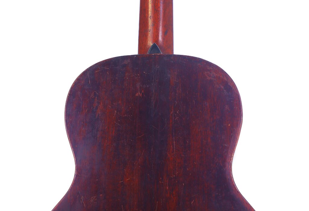 The Image Shows The Back Of A Martin 00-18 1922 Akustik Gitarre With A Dark Reddish-Brown Worn Wooden Finish, Visible Scratches And Scuffs, Set Against A Plain White Background.