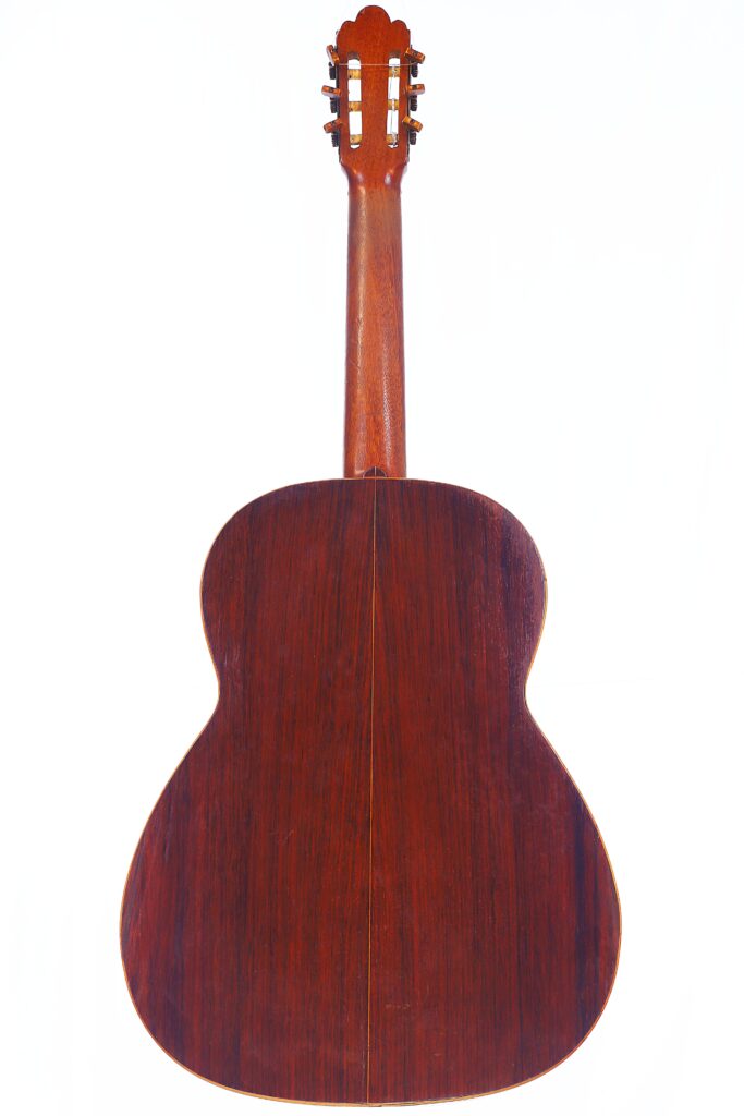 La chitarra classica Salvador Ibanez 1900 è ritratta da dietro su uno sfondo bianco e mostra il fondo, il manico e i pioli in legno.