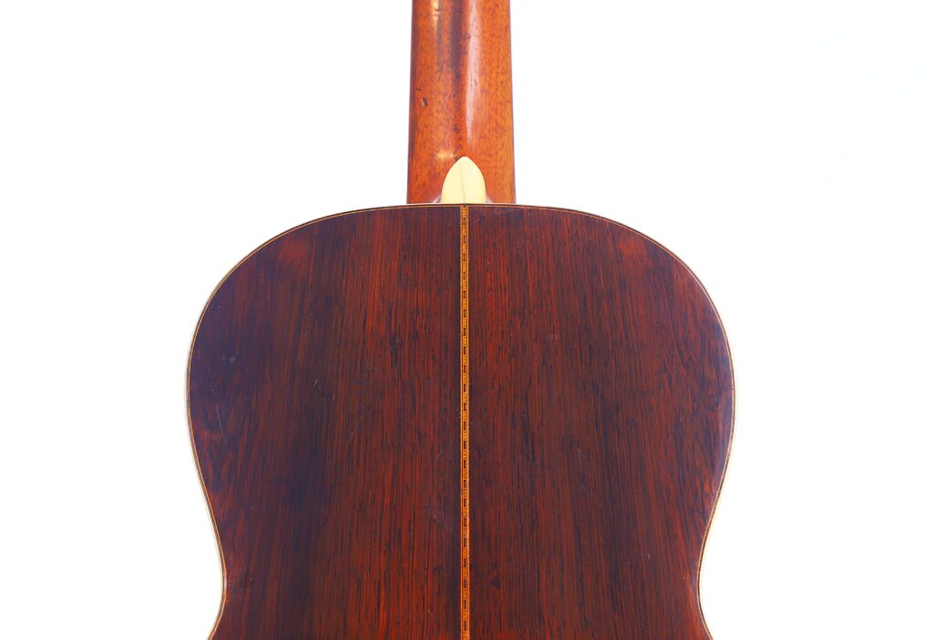 Nahaufnahme Der Rückseite Einer Martin 0-30 1917 Akustikgitarre, Die Das Polierte Dunkle Holz Und Den Zentralen Hellen Streifen Vor Einem Weißen Hintergrund Hervorhebt.