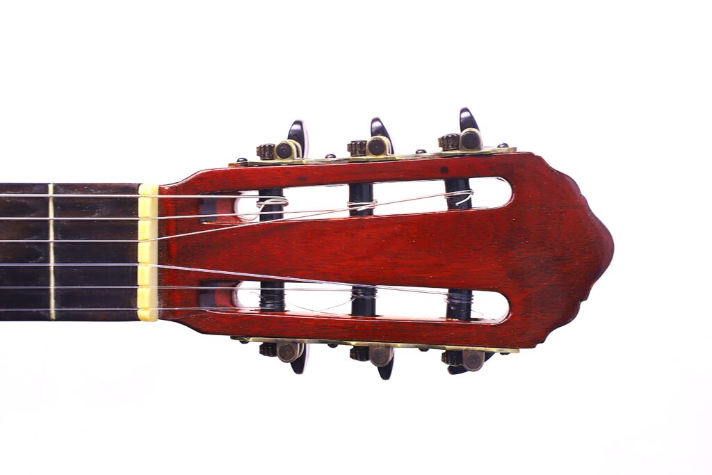 Die Kopfplatte Einer Flamenco-Gitarre Von Manuel Reyes Aus Dem Jahr 1955, Mit Stimmwirbeln Und Saiten, Fotografiert Auf Weißem Hintergrund.