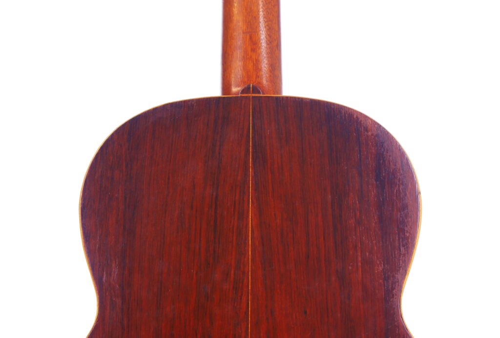 Primo piano del fondo di una chitarra classica Salvador Ibanez 1900, con finitura in legno lucido, manico e una cucitura verticale al centro su uno sfondo bianco.