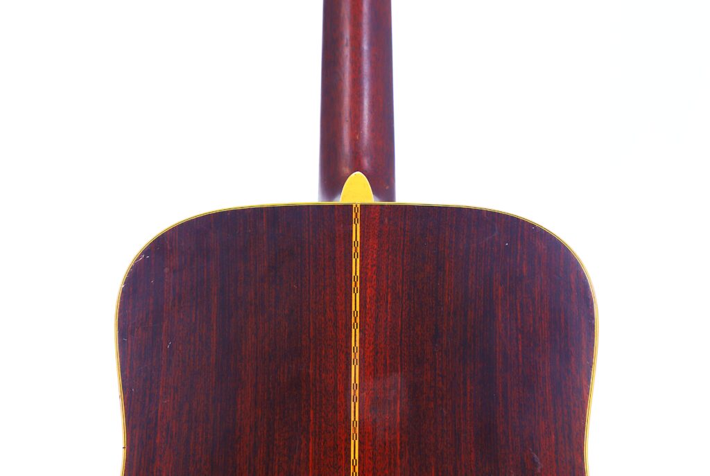 Nahaufnahme Des Bodens Und Des Halses Einer Martin D-28 1971 Akustik-Gitarre Mit Dunklem Holz, Einer Gelben Ziereinlage In Der Mitte Und Einer Gelben Zierleiste An Der Oberseite Vor Weißem Hintergrund.