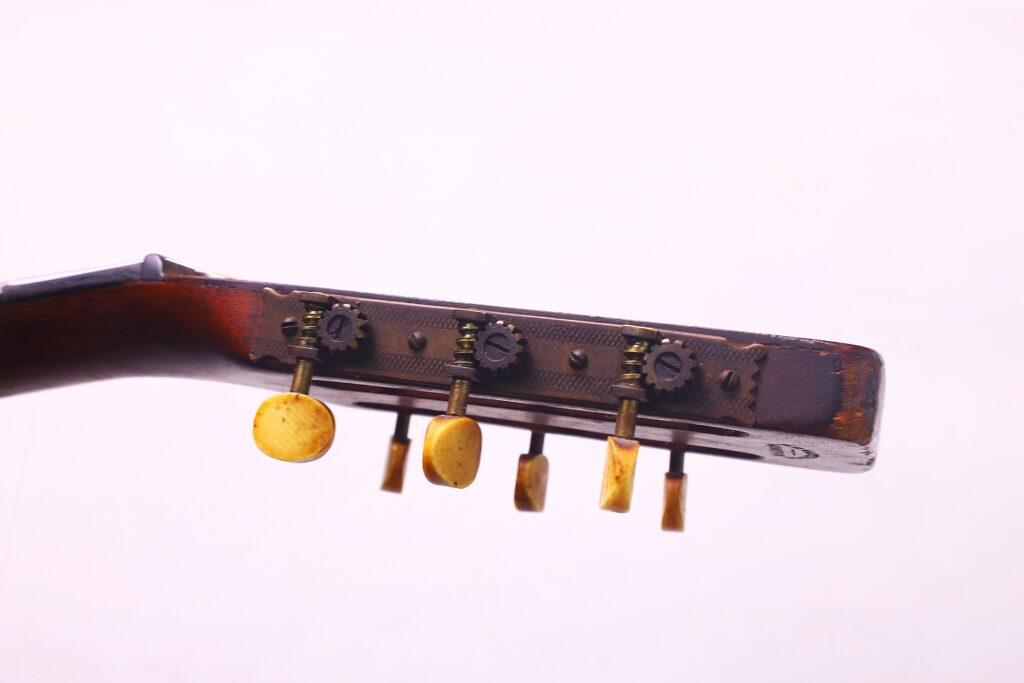 Close-Up Of The Headstock Of A Martin 00-18 1922 Akustik Gitarre, Featuring Four Yellow Tuning Pegs And Metal Tuners Against A Light Background.