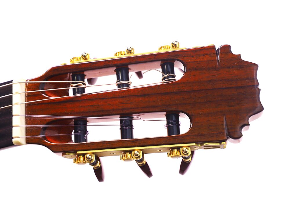 Nahaufnahme Der Kopfplatte Der Hermanos Sanchis Lopez F Especial 2025 Mod. Reyes Flamenco Gitarre Mit Hölzernen Mechaniken, Goldenen Stimmwirbeln Und Nylonsaiten Auf Weißem Hintergrund.