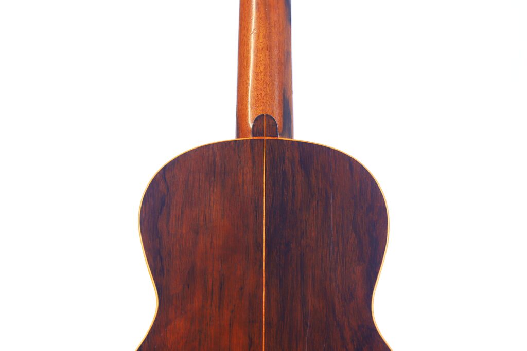 Die Abbildung Zeigt Die Rückseite Einer Julián Gómez Ramírez Klassische Gitarre Von 1933 Aus Dunklem, Poliertem Holz Mit Einer Einzigen Hellen Linie, Die Vertikal In Der Mitte Verläuft, Vor Einem Schlichten Weißen Hintergrund.