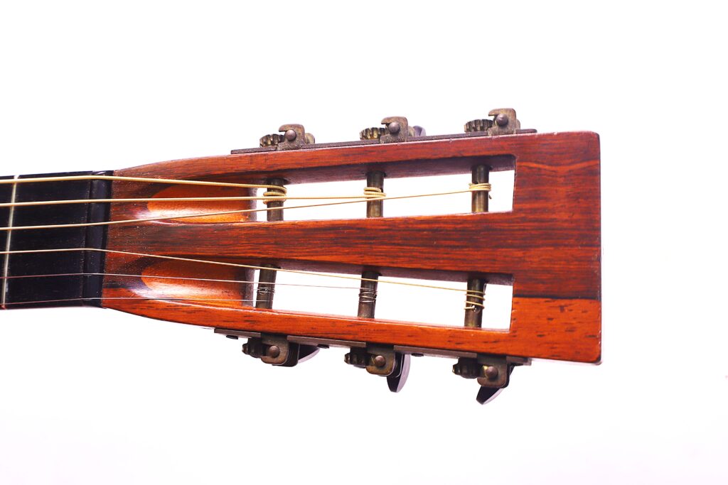 Nahaufnahme Der Kopfplatte Der Washburn 1894 Parlor Akustik Gitarre Mit Drei Stimmwirbeln Pro Seite Und Nylonsaiten Vor Einem Weißen Hintergrund.