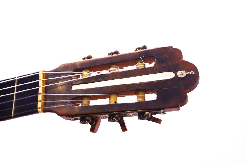 Primo piano della paletta di una chitarra classica Salvador Ibanez 1900, che mostra i pioli di accordatura, le corde e parte della tastiera su uno sfondo bianco.