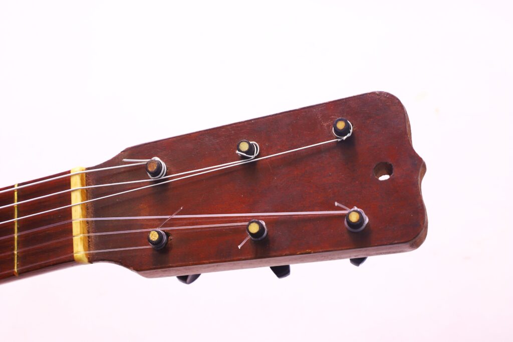 1953 年 Jose Ramirez 创作的弗拉门戈吉他木制琴头特写,纯白背景下有六个调音踏板和琴弦。.