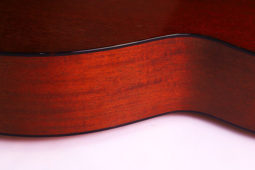 Nahaufnahme Der Collings Om1 Jl 2019 Akustik-Gitarre, Die Den Glatten, Polierten, Rotbraunen Holzkorpus Mit Einer Sanften Wölbung Und Einer Eleganten Schwarzen Zierleiste Entlang Der Kante Hervorhebt.