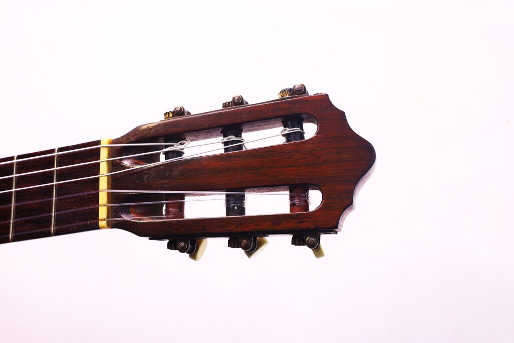 Nahaufnahme Der Kopfplatte, Der Stimmwirbel, Des Halses Und Der Saiten Einer Julián Gómez Ramírez 1933 Klassische Gitarre Vor Einem Schlichten Weißen Hintergrund.