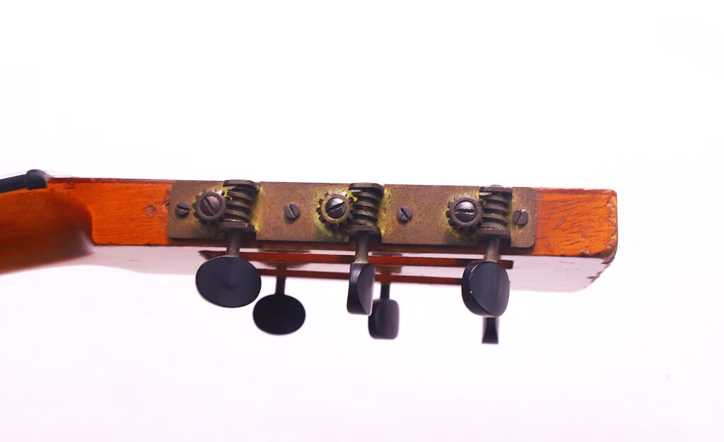 Nahaufnahme Der Stimmwirbel Und Der Kopfplatte Einer Washburn 1894 Parlor Akustik Gitarre, Dargestellt Vor Einem Schlichten Weißen Hintergrund. Die Gealterten Stimmmechaniken Haben Sichtbare Metallteile Und Schwarze Knöpfe.