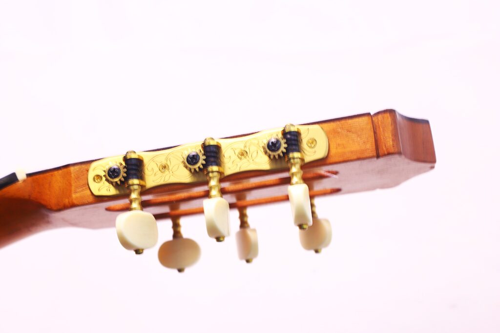 Nahaufnahme Der Kopfplatte Einer Oscar Orozco 2023 Santos Hernández Flamenco-Gitarre Mit Goldenen Stimmwirbeln Und Elfenbeinfarbenen Knöpfen Vor Einem Schlichten, Hellen Hintergrund.