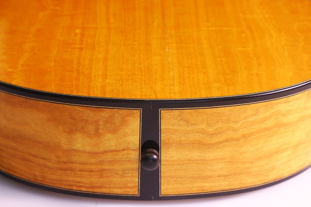 Nahaufnahme Des Bodens Der Grobert Romantikgitarre 2016 Von Yoann Charbonnier. Hervorzuheben Sind Die Holzmaserung, Die Glänzende Oberfläche Und Der Mittig Angeordnete Schwarze Bandknopf In Der Nähe Des Randes.