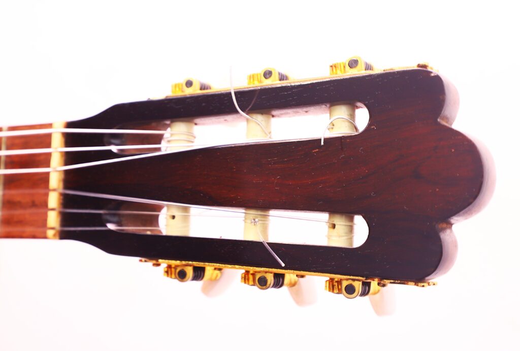 Nahaufnahme Der Kopfplatte Der Vicente Tatay Alabau 1920 Klassische Gitarre Mit Nylonsaiten, Goldenen Wirbeln Und Einer Dunklen Holzoberfläche Auf Weißem Grund.