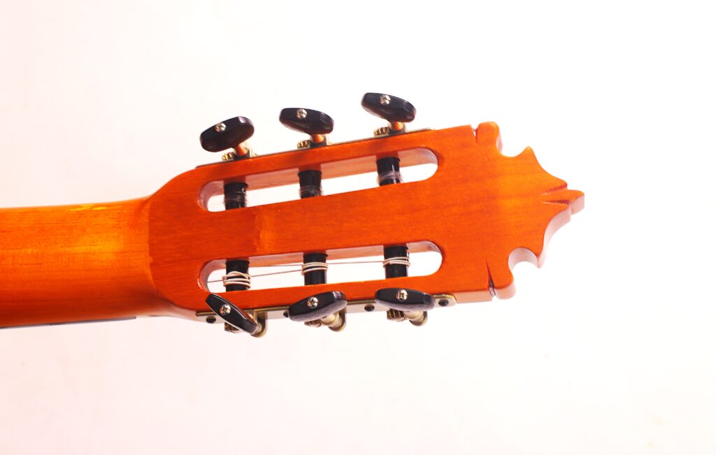 Nahaufnahme Der Graciliano Perez 2025 Flamenco-Gitarre Mit Kopfplatte Und Stimmwirbeln, Wobei Die Holzoberfläche Und Die Saitenwicklungen Vor Einem Schlichten Weißen Hintergrund Hervorgehoben Werden.