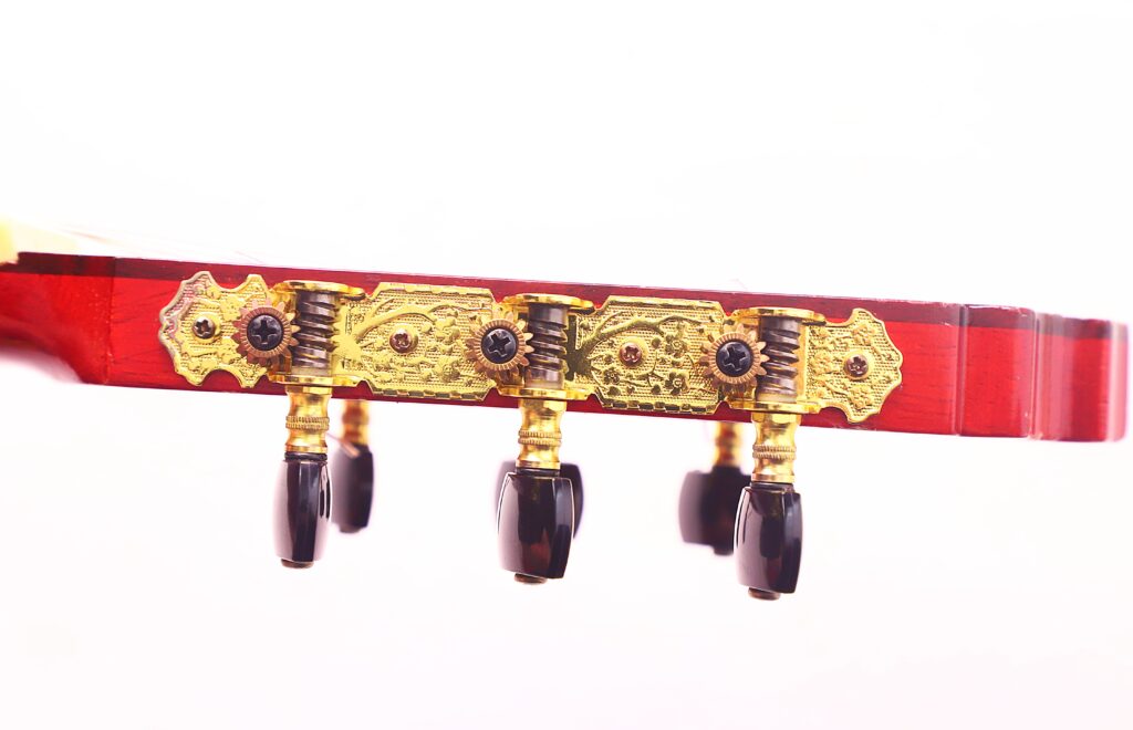 Nahaufnahme Der Stimmwirbel An Der Kopfplatte Einer Manuel Guillena 2017 Blanca Flamenco-Gitarre, Mit Verzierten Goldplatten Und Drei Schwarzen Stimmschlüsseln Vor Weißem Hintergrund.