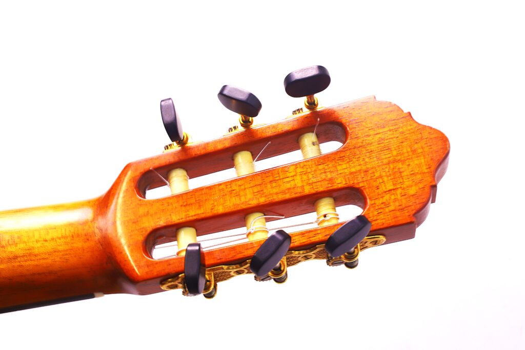 Nahaufnahme Der Stimmwirbel Und Der Kopfplatte Einer Lester Devoe 1996 Negra Flamenco Gitarre Vor Einem Weißen Hintergrund. Das Holz Hat Eine Warme, Polierte Oberfläche Und Die Schwarzen Stimmwirbel Heben Sich Elegant Ab.