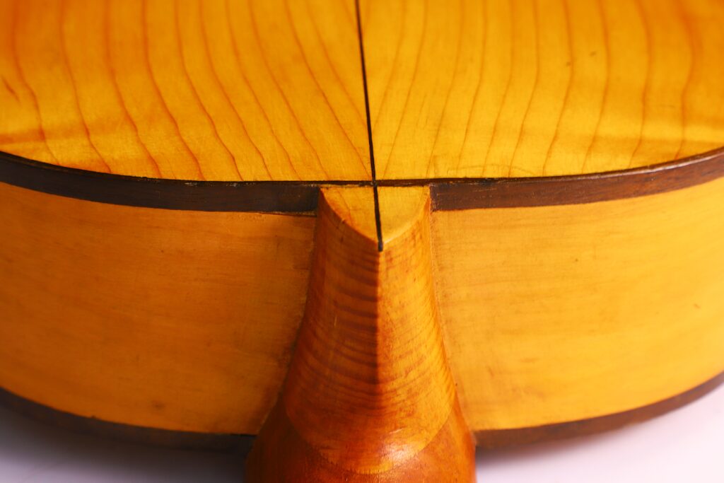 何塞-拉米雷斯(Jose Ramirez)1953 年制作的弗拉门戈吉他背面特写,突出了光滑的黄色木纹和两半吉他交接处的中心接缝。.