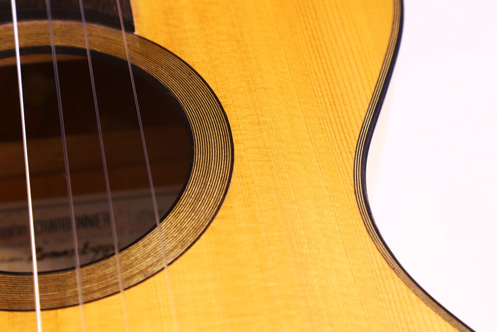 Nahaufnahme Einer Grobert Romantikgitarre 2016 Von Yoann Charbonnier Mit Stahlsaiten, Einem Teil Des Schalllochs Mit Konzentrischen Ringen, Einer Hellen Holzmaserung Und Einem Weißen Schlagbrett Auf Der Rechten Seite.