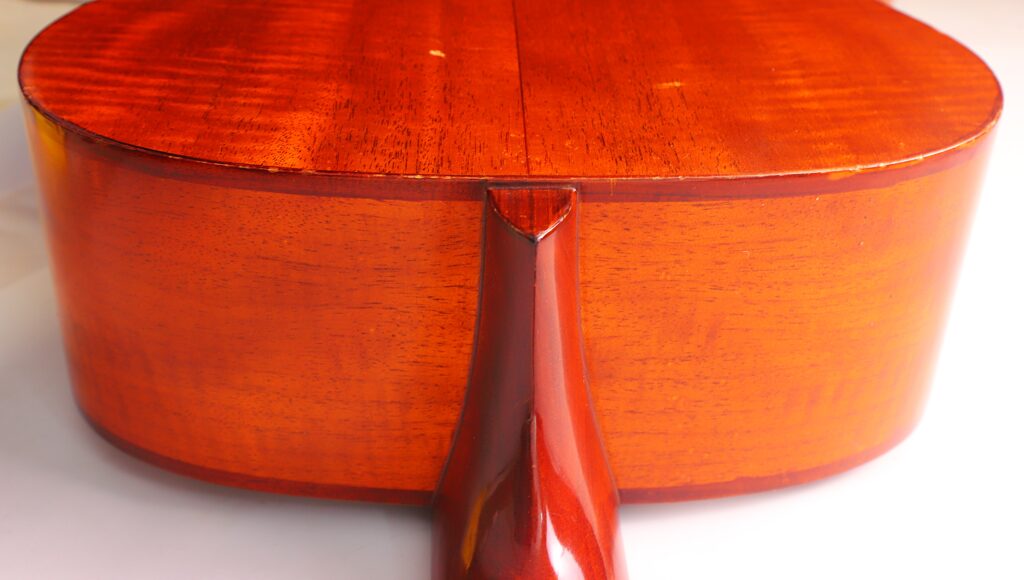 Nahaufnahme Des Bodens Und Des Halses Der Lowden F-9 1980 Akustik Gitarre, Die Die Glänzende, Polierte Oberfläche Und Die Reiche Rötlich-Braune Holzmaserung Zur Geltung Bringt.