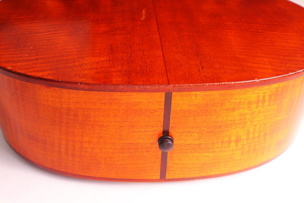 Nahaufnahme Der Rückseite Und Der Seite Einer Lowden F-9 1980 Akustik-Gitarre, Die Die Polierte Holzoberfläche Mit Einem Schwarzen Gurtknopf In Der Mitte Zeigt.