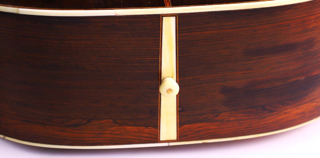 Nahaufnahme Der Unterseite Einer Martin 0-30 1917 Akustik-Gitarre, Die Das Holzfinish, Den Cremefarbenen Endstreifen Und Den Cremefarbenen Endpin In Der Mitte Hervorhebt.