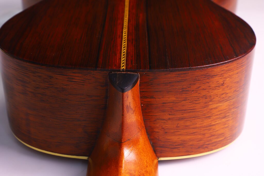 Nahaufnahme Des Bodens Und Der Zargen Der Washburn 1894 Parlor Akustik Gitarre. Hervorzuheben Ist Die Stelle, An Der Der Hals Auf Den Korpus Trifft, Mit Ihrer Polierten Holzmaserung Und Detaillierten Verarbeitung.