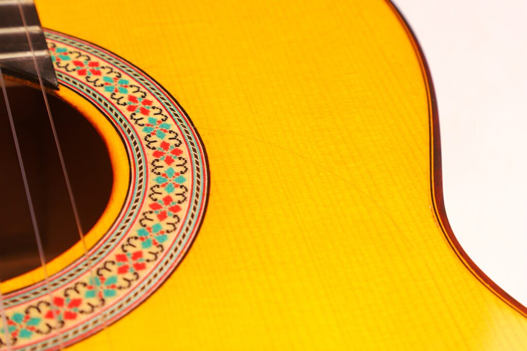 Nahaufnahme Des Korpus Der Graciliano Perez 2025 Flamenco-Gitarre Mit Dem Schallloch, Der Rosette Und Den Saiten Vor Einem Hellen Hintergrund.