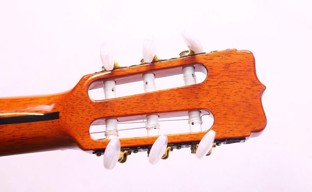 Nahaufnahme Der Kopfplatte Der José Ramírez Rb-A 636 Klassische Gitarre Mit Weißen Wirbeln, Stimmmechaniken Und Saiten Vor Einem Schlichten Weißen Hintergrund.