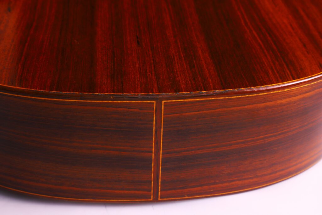 Nahaufnahme Des Bodens Und Der Seite Einer Lester Devoe 1996 Negra Flamenco Gitarre. Hervorzuheben Sind Die Reiche Braune Holzmaserung, Die Glatt Polierte Oberfläche Und Die Feinen Gelblichen Einfassungen.