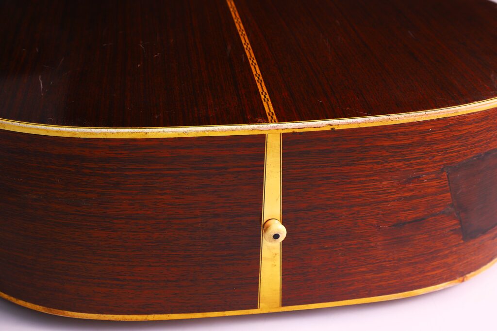 Nahaufnahme Der Rückseite Und Der Seite Einer Martin D-28 1971 Akustik Gitarre. Hervorzuheben Sind Die Polierte Holzmaserung, Der Dekorative Streifen In Der Mitte, Das Cremefarbene Binding Und Ein Kleiner Gurtknopf Am Unteren Rand.