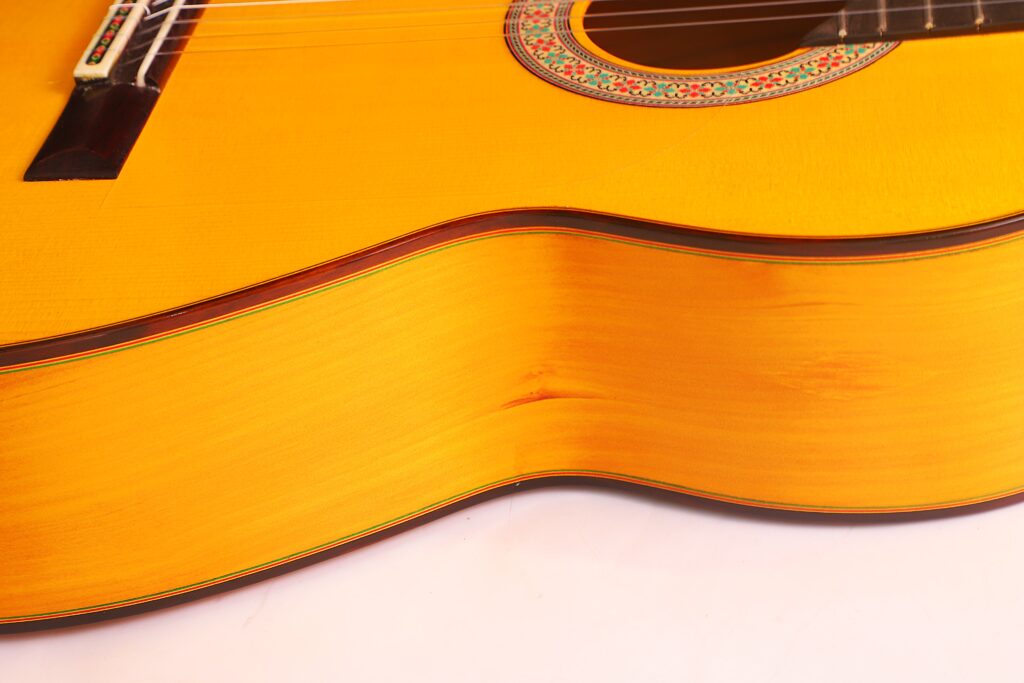 Nahaufnahme Der Flamenco-Gitarre Graciliano Perez 2025, Die Die Hölzerne Struktur, Die Saiten Und Einen Teil Der Verzierten Schalllochrosette Vor Weißem Hintergrund Zeigt.