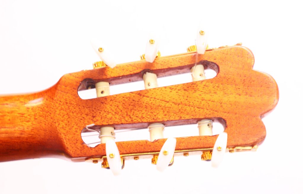 Nahaufnahme Der Kopfplatte Einer Vicente Tatay Alabau 1920 Klassische Gitarre Mit Sechs Weißen Stimmwirbeln, Goldenen Beschlägen Und Einer Holzoberfläche Vor Weißem Hintergrund.