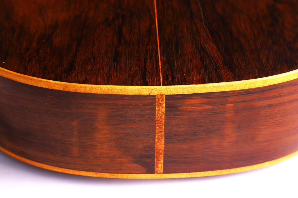 Nahaufnahme Des Bodens Und Der Seite Der Julián Gómez Ramírez 1933 Klassische Gitarre, Mit Dunklem, Poliertem Holz Mit Natürlicher Maserung Und Hellem Einband Entlang Der Kanten.