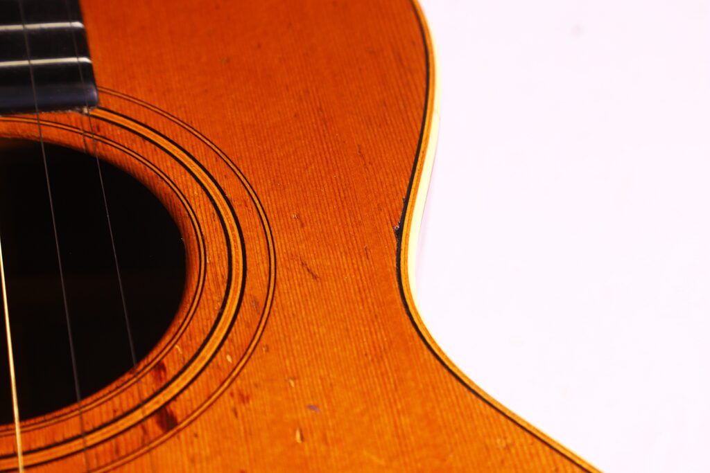 Nahaufnahme Des Korpus Der Washburn 1894 Parlor Akustik Gitarre Mit Schallloch, Saiten Und Holzmaserung, Wobei Ein Teil Der Gitarre Mit Einem Weißen Hintergrund Verschmilzt.