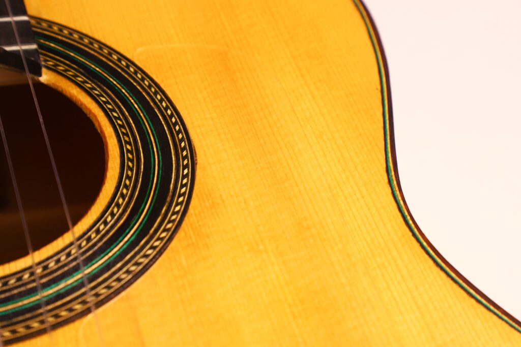 Nahaufnahme Des Korpus Der Oscar Orozco 2023 Santos Hernández Flamenco-Gitarre, Die Das Schallloch, Die Dekorative Rosette, Die Detaillierte Holzmaserung Und Die Saiten Auf Einem Hellen Hintergrund Zeigt. Aufwändige Handwerkskunst Und Designdetails Werden Hervorgehoben.