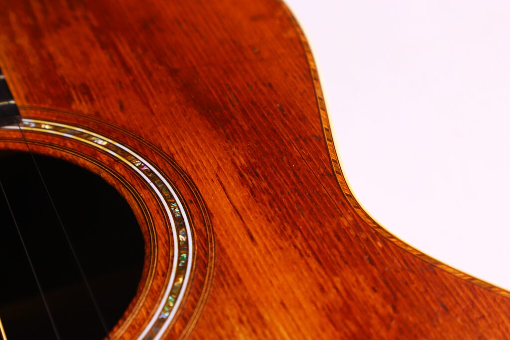 Nahaufnahme Des Korpus Der Martin 0-30 1917 Akustik Gitarre, Die Die Hölzerne Textur, Das Satte Braune Finish Und Die Dekorative Schalllocheinlage Vor Einem Schlichten Weißen Hintergrund Zeigt.