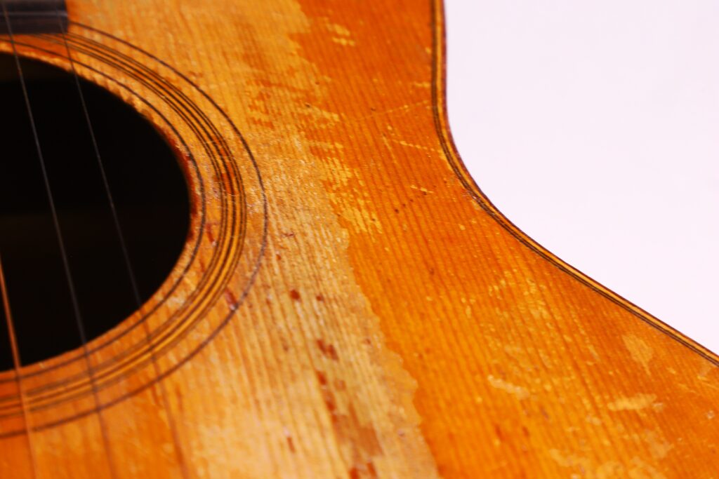 Nahaufnahme Einer Martin 0-18 1926 Akustik Gitarre, Die Das Schallloch Und Den Korpus Zeigt, Mit Abgenutztem Holz Und Kratzern, Die Den Häufigen Gebrauch Widerspiegeln. Vor Einem Weißen Hintergrund.