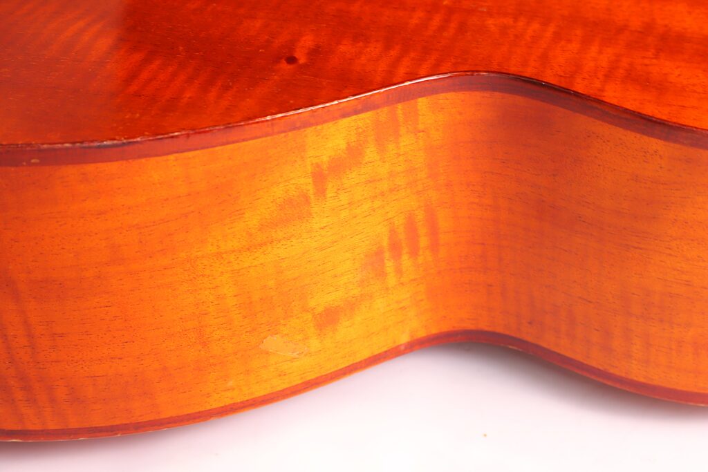 Nahaufnahme Der Seite Einer Lowden F-9 1980 Akustik-Gitarre, Wobei Die Glänzende Orange-Braune Lackierung Und Die Glatte, Gewölbte Holzoberfläche Hervorgehoben Werden.