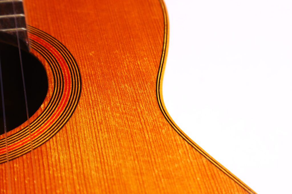 Nahaufnahme Der Julián Gómez Ramírez 1933 Klassische Gitarre, Die Den Akustischen Korpus Mit Kreisförmiger Schalllochverzierung, Die Holzmaserung Und Einen Teil Des Halses Vor Einem Weißen Hintergrund Zeigt.