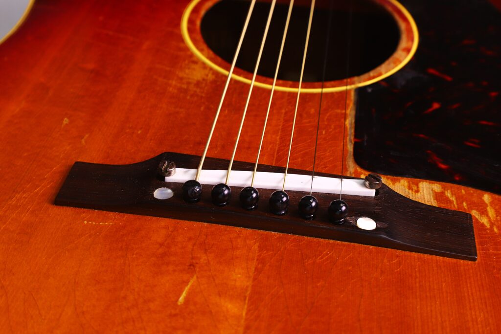Nahaufnahme Der Gibson J-45 1962 Akustik Gitarre Mit Steg, Sattel Und Saiten Auf Einem Warmen Holzkorpus Mit Einem Teilweise Sichtbaren Schwarzen Schlagbrett.