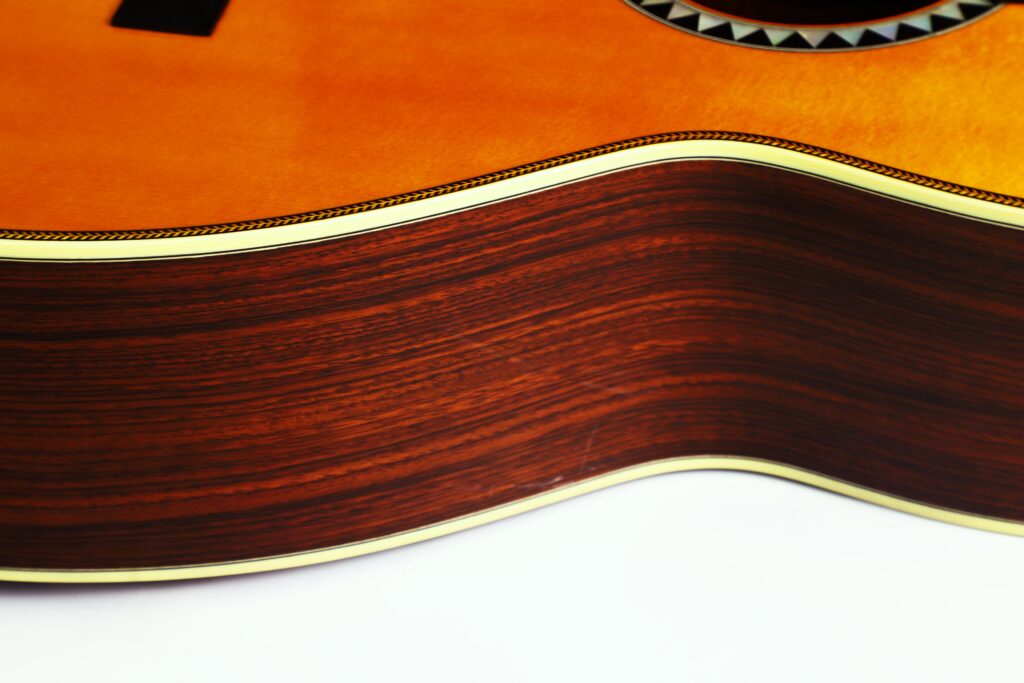 Nahaufnahme Der Seite Einer Martin 0-28 Ian Anderson Akustik Gitarre, Die Den Gewölbten Holzkorpus Mit Glänzender Oberfläche Und Cremefarbenem Binding Vor Weißem Hintergrund Zeigt.