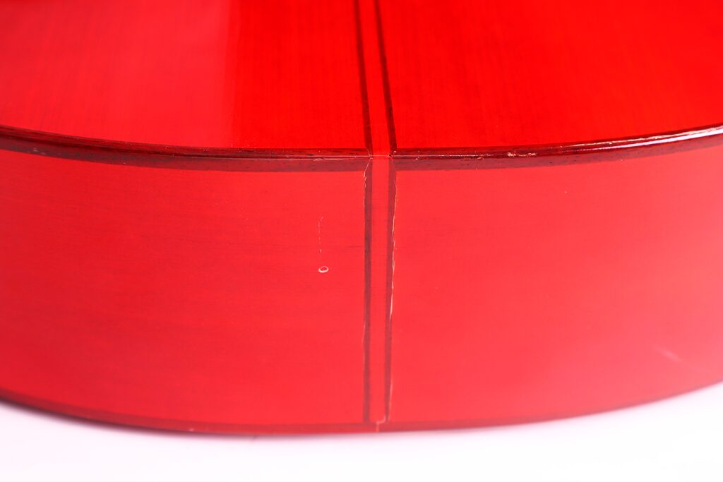 Nahaufnahme Der Seite Einer Polierten, Roten Manuel Guillena 2017 Blanca Flamenco-Gitarre, Die Eine Naht Zeigt, An Der Zwei Holzstücke Mit Glatter, Glänzender Oberfläche Aufeinandertreffen.